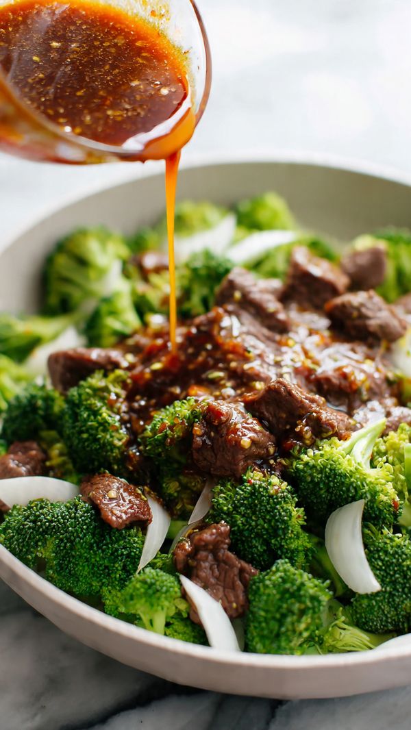 A white pan filled with bright green broccoli florets forming the bottom layer, topped with bite-sized pieces of cooked brown meat scattered over the broccoli, with thin white onion slices mixed in; a woman's hand is pouring a thick, dark reddish-brown sauce with visible minced garlic over the meat and vegetables, creating a glossy, rich coating. The whole scene sits on a white marbled surface. photo taken with an iphone --ar 4:5 --v 7