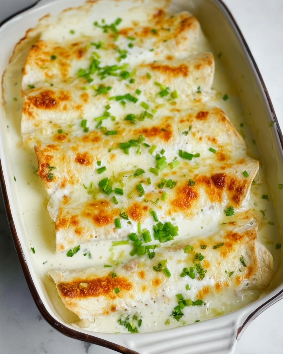 The dish shows two rolled tortillas placed side by side on a white plate, covered with a thick layer of creamy melted cheese that is slightly browned on top. The cheese looks smooth and soft with some golden spots, and there are small green pieces of chopped scallion sprinkled evenly over the cheese. Inside the rolled tortillas, chunks of white meat are visible, surrounded by a creamy sauce with a light texture. A fork rests on the edge of the plate, set against a white marbled surface in the background. photo taken with an iphone --ar 4:5 --v 7