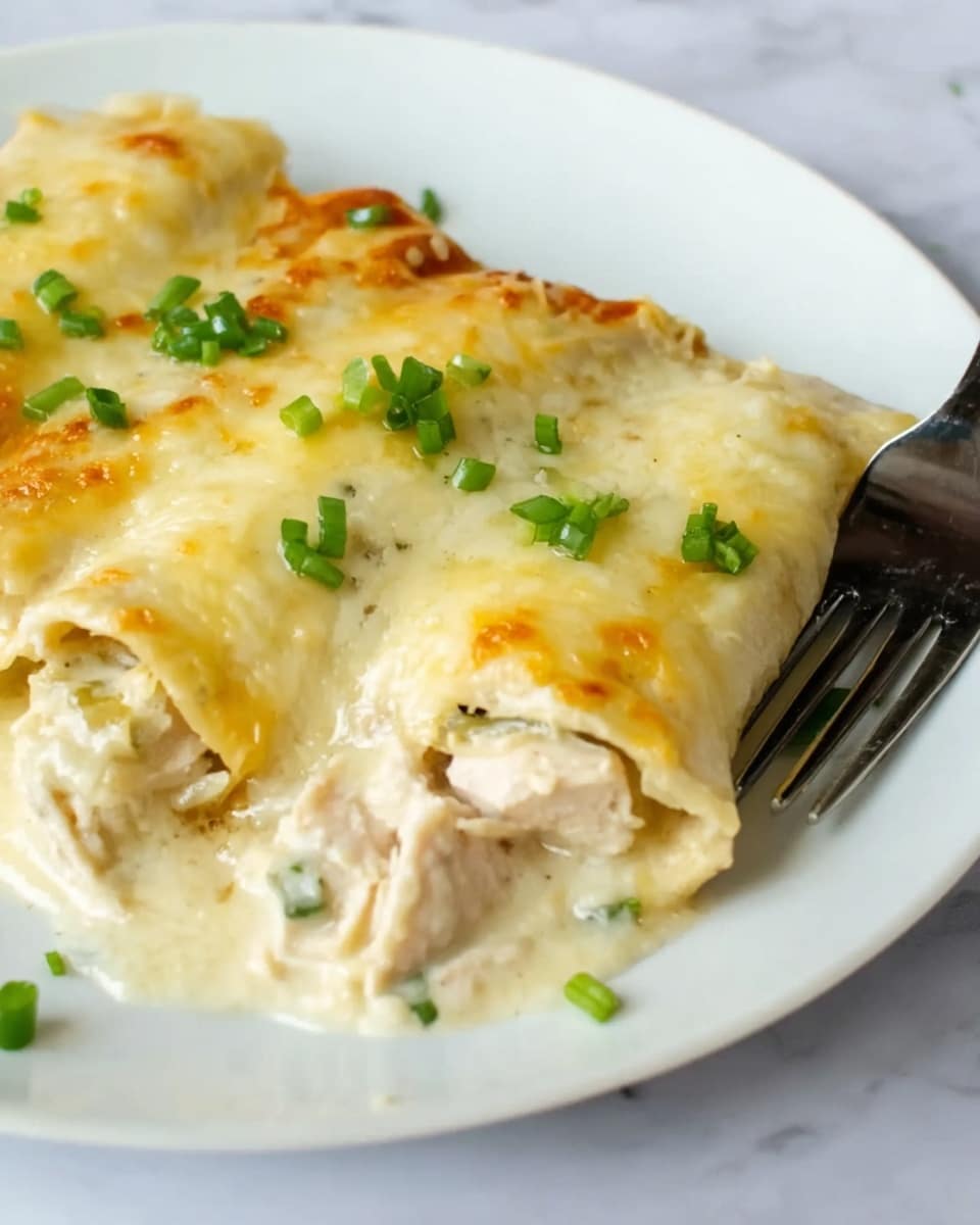 The image shows a white dish filled with six rolled tortillas covered in melted golden-brown cheese. The tortillas are slightly browned on top, with creamy white sauce around and between them. Bright green chopped onions are sprinkled evenly over the top, adding a fresh pop of color. The dish has a rich, creamy texture with the cheese looking soft and bubbly. The dish sits on a white marbled surface. photo taken with an iphone --ar 4:5 --v 7