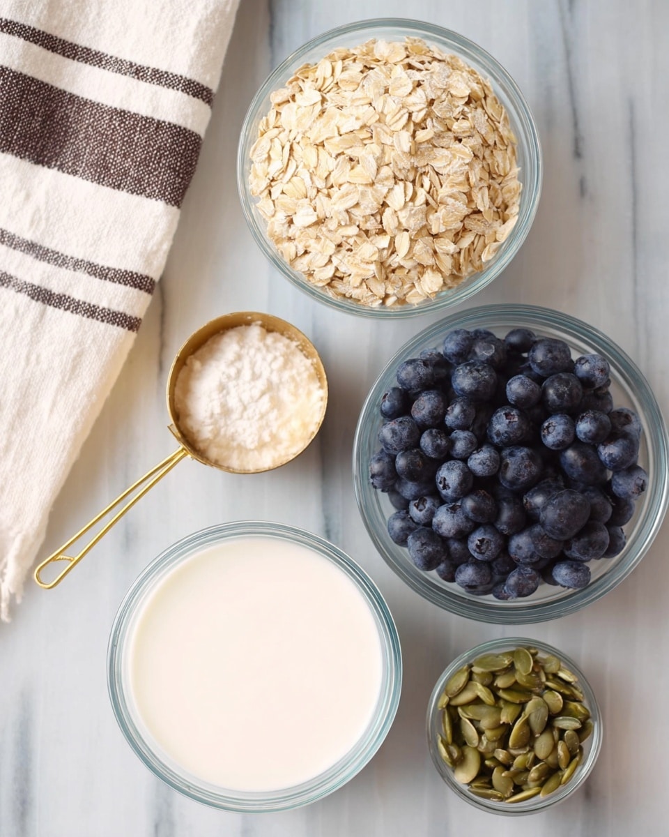 The image shows five clear glass bowls and a gold measuring cup arranged on a white marbled surface. The largest bowl at the bottom holds a smooth, white liquid with a creamy texture. Above it, a medium bowl contains light beige rolled oats with a rough, flaky texture. To the top right is another medium bowl filled with round, dark blue blueberries covered with a soft bloom. At the bottom right, a small bowl has beige elongated nuts or seeds with a smooth texture. On the left side, a gold measuring cup is filled with a white, lumpy substance. A white cloth with black and brown stripes is partially visible in the top left corner. Photo taken with an iphone --ar 4:5 --v 7