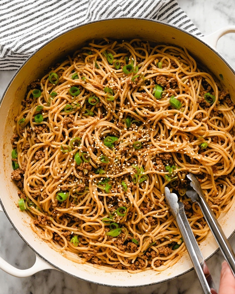 A large white pot filled with long, light brown noodles mixed with small pieces of cooked ground meat that have a slightly darker brown color. The noodles are scattered with bright green chopped scallions and small white sesame seeds. A pair of metal tongs is partially inserted into the noodles on the right side, while a woman's hand holding a spoon is visible on the left side, resting near the pot. The background has a white marbled texture with a striped cloth napkin partially visible in the top left corner. photo taken with an iphone --ar 4:5 --v 7