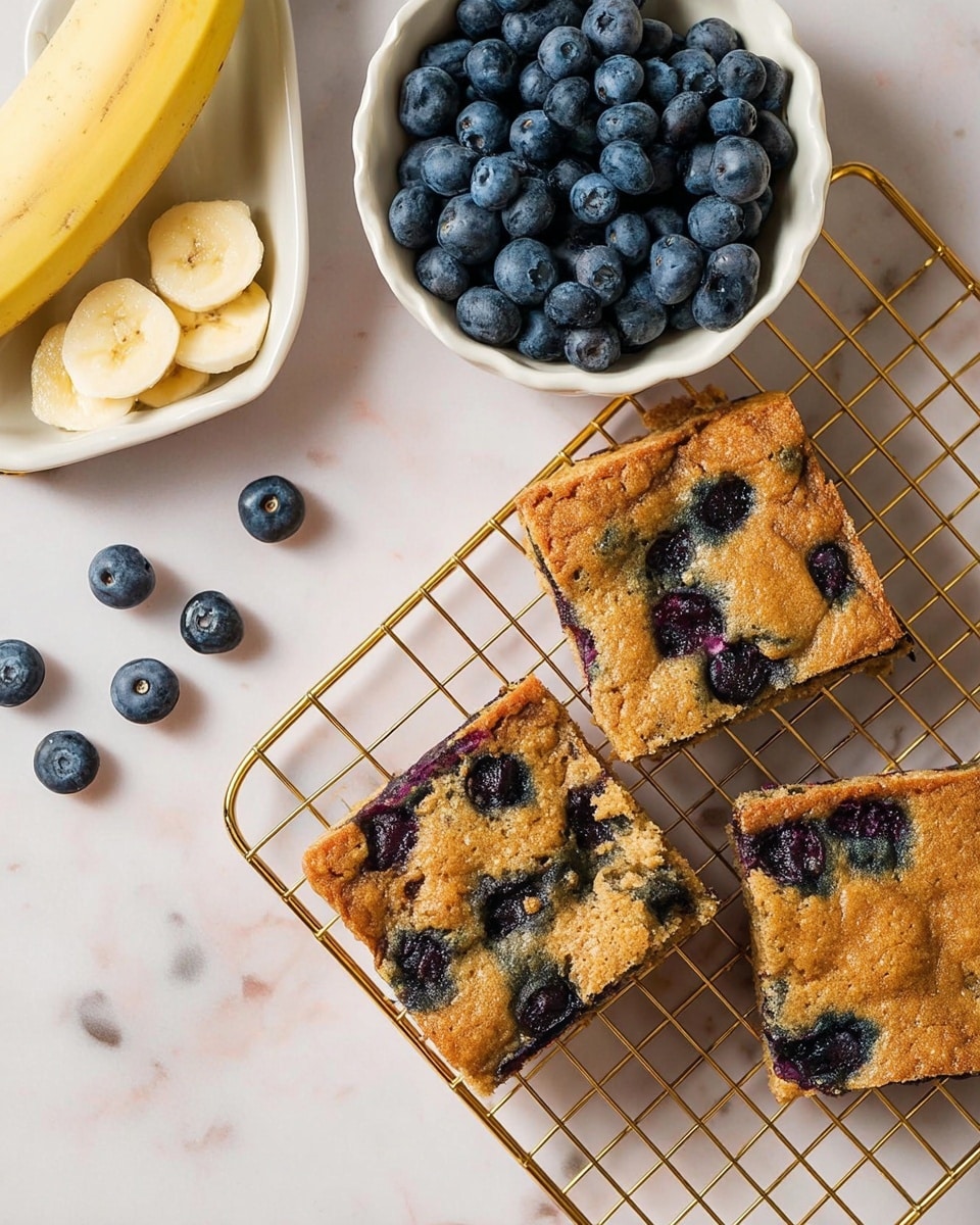 A stack of four square bars is placed on a white plate on a white marbled surface. Each bar has a golden-brown top and bottom layer with a soft, moist middle layer filled with deep blue and purple blueberries that slightly bleed into the surrounding golden dough. The blueberries create uneven, colorful pockets through the bars. On top of the stack, three whole blueberries sit as decoration, with one blueberry resting next to the stack on the plate. The background is softly blurred, creating focus on the bars. Photo taken with an iphone --ar 4:5 --v 7