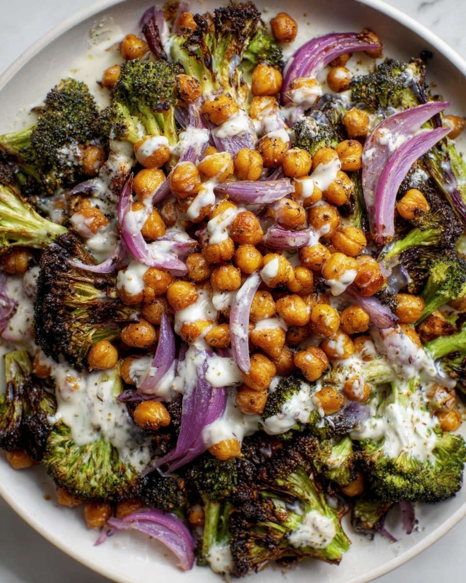 The image shows a white plate filled with a colorful roasted vegetable medley on a white marbled surface. The bottom layer contains caramelized green broccoli with some slightly crispy edges. On top of this is a thick layer of golden brown roasted chickpeas, evenly spread across the vegetables. Light purple sliced onions are scattered thinly over the chickpeas, adding contrast. Some creamy white sauce is drizzled over the entire dish, creating a smooth texture that lightly covers the vegetables and chickpeas. The vegetables have a roasted, slightly charred look with a mix of green, brown, golden, and purple colors. photo taken with an iphone --ar 4:5 --v 7