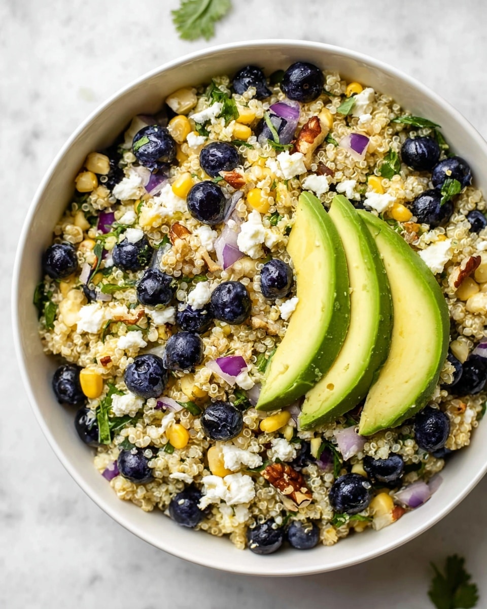 A white bowl full of a quinoa salad sitting on a white marbled surface, with three big slices of green avocado placed evenly on top. The salad has one base layer of small, pale quinoa grains mixed with bright yellow corn kernels and small pieces of diced purple onion. Scattered all over this are plump, deep blue blueberries and chunks of white cheese. There are small pieces of green leafy herbs sprinkled throughout along with some brown nuts added for texture. The scene is bright and fresh with the different colors and textures blending well together. photo taken with an iphone --ar 4:5 --v 7