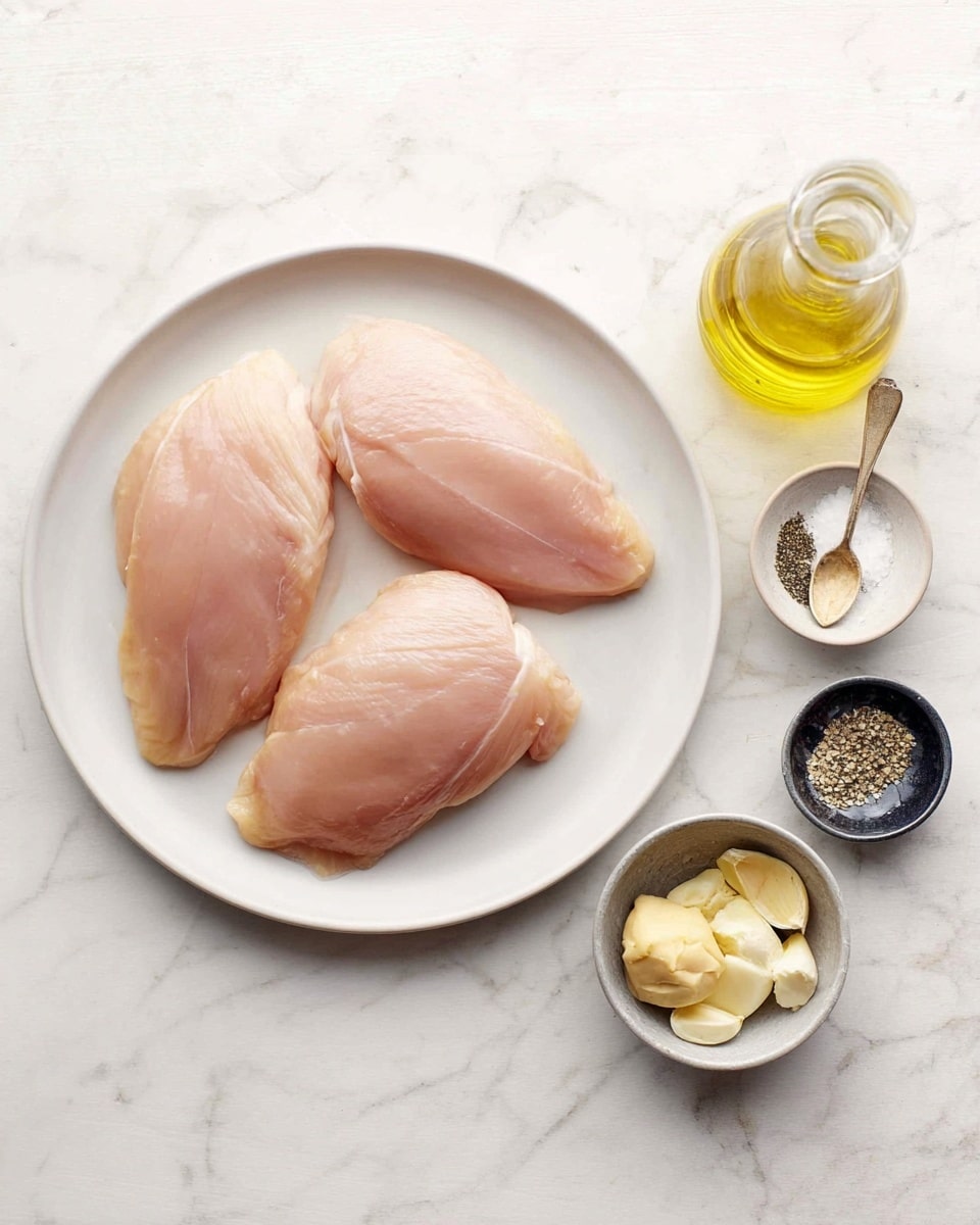 The image shows three pieces of raw chicken arranged on a white plate, placed on a white marbled surface. To the right of the plate, there is a small clear bottle of olive oil, a small metal bowl with a spoon containing creamy mustard, three peeled garlic cloves, and a small round plate half black and half white holding salt and black pepper. The chicken pieces are pale pink with smooth textures, and the surrounding ingredients are neatly spaced. photo taken with an iphone --ar 4:5 --v 7