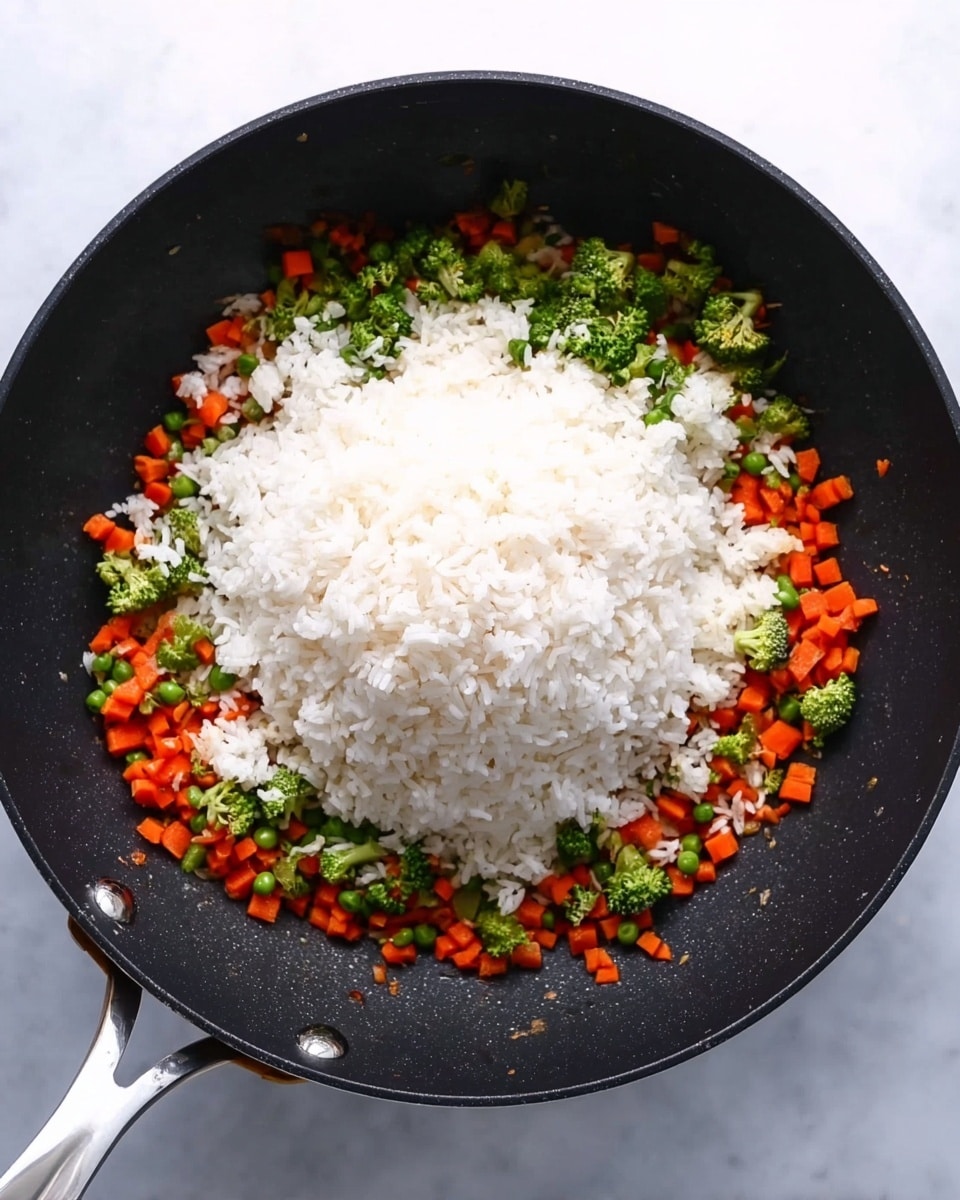 A black frying pan filled with three visible layers: the bottom layer has small diced orange carrots evenly spread, the middle layer shows small green broccoli florets scattered on top of the carrots, and the top layer has a large mound of white cooked rice piled right in the center. The white marbled surface is underneath the pan. The pan has a silver handle. Photo taken with an iphone --ar 4:5 --v 7