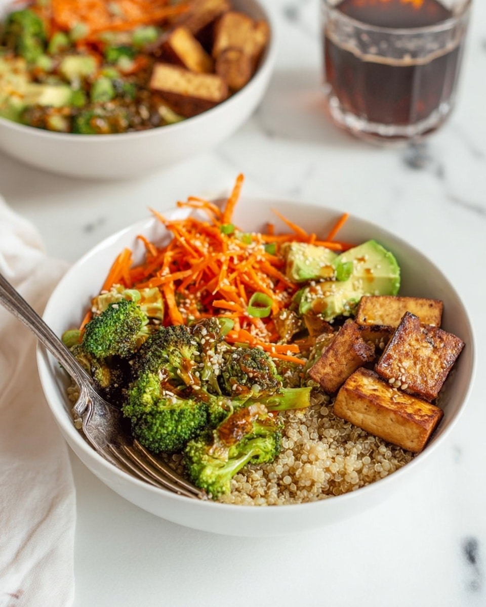 The dish shows a white bowl filled with three main layers: at the bottom, there's a bed of light beige quinoa with a slightly grainy texture; on top of this, bright orange shredded carrots and chunks of pale green avocado are scattered, adding vibrant color and creaminess; lastly, dark green broccoli florets and several pieces of golden-brown tofu with a grilled texture are placed around one side, creating height and variety. A fork is inside the bowl on the left side, and in the background, there is another similar bowl and a glass with a dark drink, all set on a white marbled surface. Photo taken with an iphone --ar 4:5 --v 7