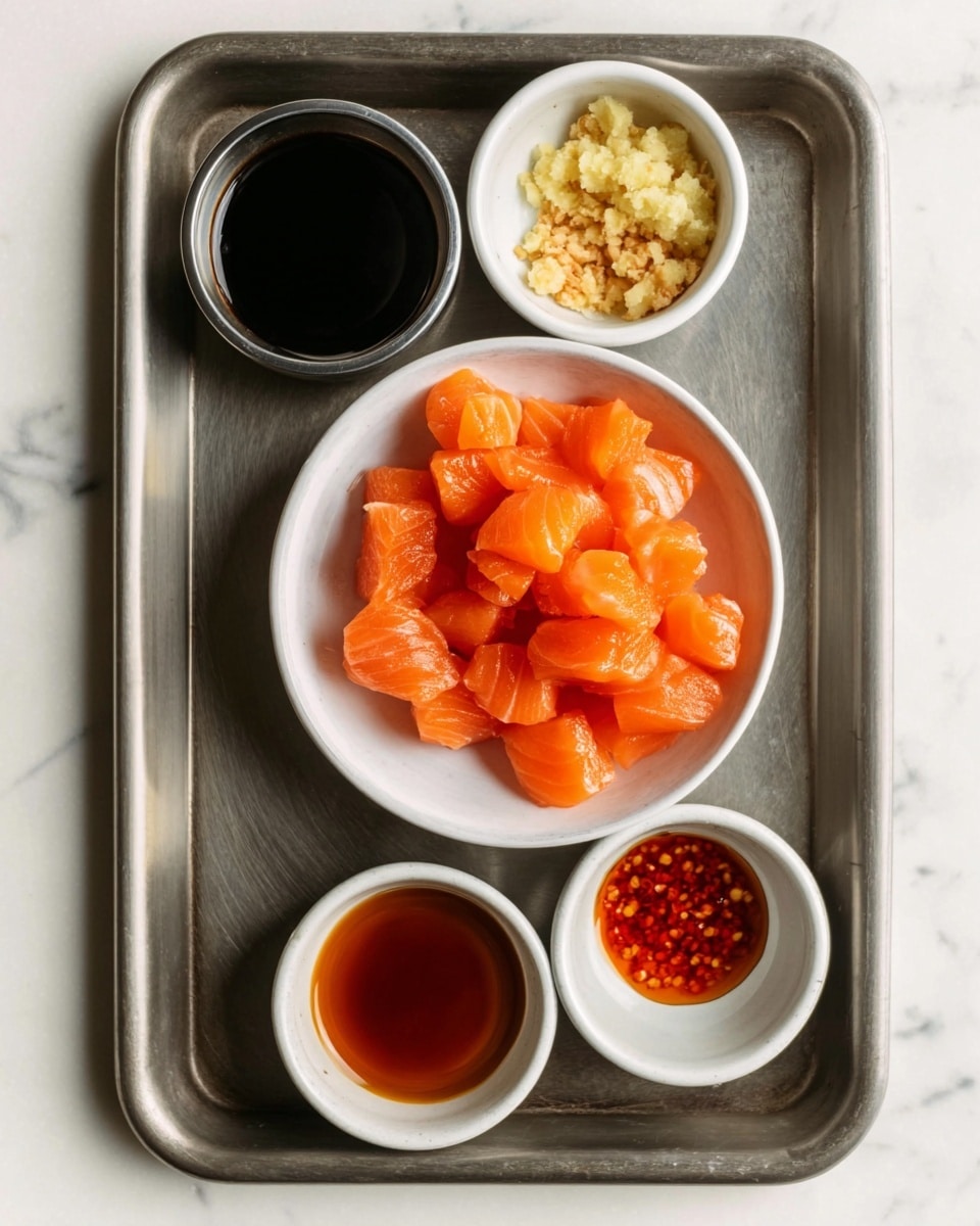 The image shows a plain metal tray holding five small round white bowls arranged with one in the center and the other four around it, placed on a white marbled surface. The center bowl is filled with bright orange, cubed raw salmon pieces that have a smooth, slightly shiny texture. The surrounding four bowls hold different sauces and condiments: a dark soy sauce in the top left bowl, finely chopped light ginger in the top right small bowl, a shiny golden-brown sauce in the middle left bowl, a red spicy-looking sauce in the bottom right bowl, and an empty bowl at the bottom left. The setup is minimalist, clean, and focused on the ingredients. Photo taken with an iphone --ar 4:5 --v 7
