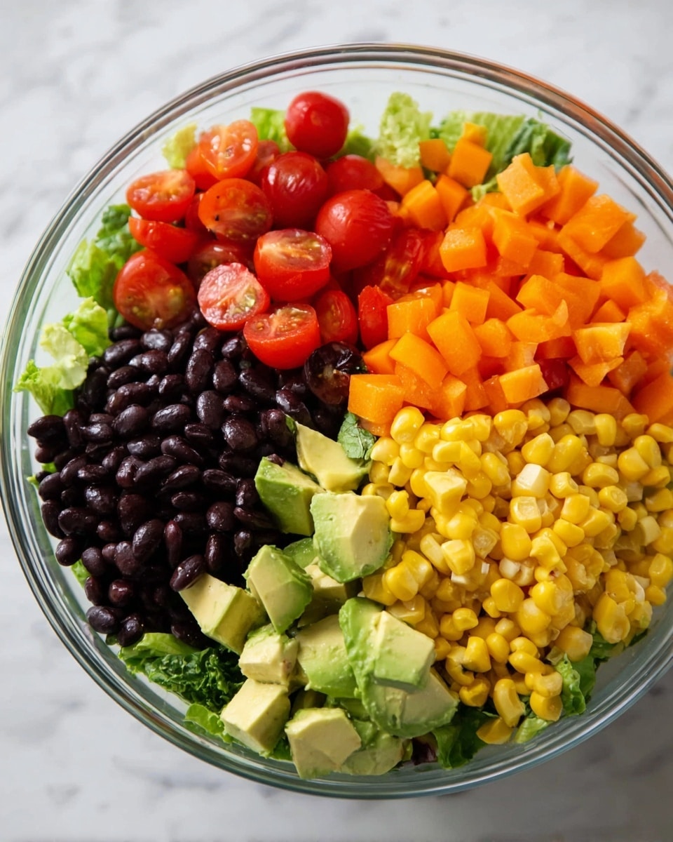 A clear glass bowl on a white marbled surface holds a colorful salad arranged in neat sections. At the bottom, there is a layer of green lettuce. On top, there are five distinct layers: black beans in shiny black, halved red cherry tomatoes, bright yellow corn, diced orange bell peppers, and chunks of light green avocado. The colors are vibrant and fresh, creating a visually appealing mix. Photo taken with an iphone --ar 4:5 --v 7