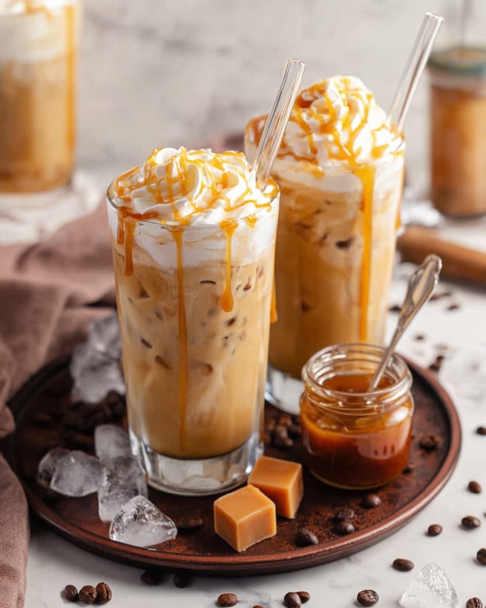 This image shows two tall clear glasses filled with light brown iced coffee, each filled with ice cubes and topped with a swirl of white whipped cream drizzled with golden caramel sauce. Each glass has a clear glass straw. The glasses sit on a round dark brown tray that also holds a small jar of caramel sauce with a spoon inside, two caramel candy squares, and scattered dark brown coffee beans. The setting is on a white marbled surface with some ice cubes and coffee beans spread around, and a blurred background with another similar glass. Photo taken with an iphone --ar 4:5 --v 7