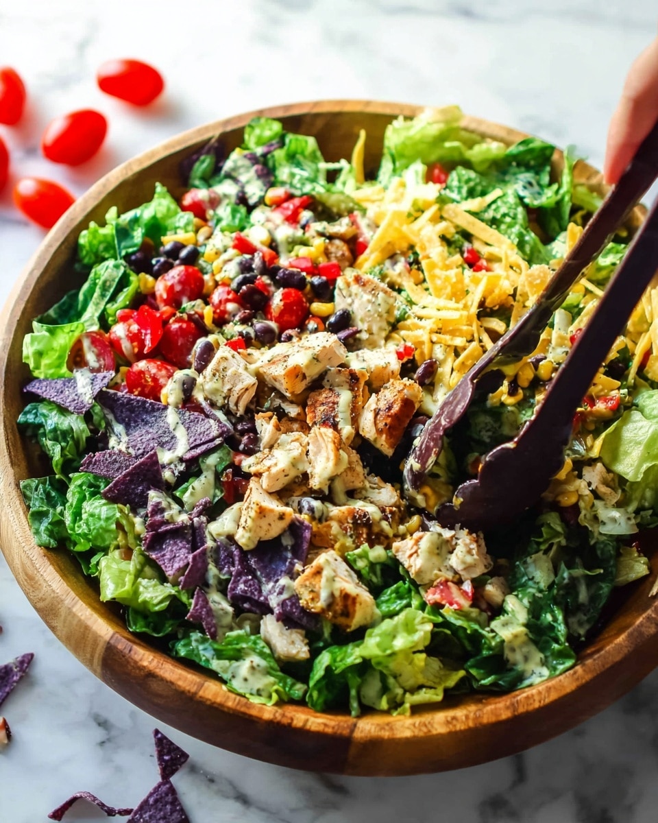 A large wooden bowl filled with a fresh mixed salad sits on a white marbled surface. The salad has many layers: a base of bright green lettuce leaves, topped with chunks of grilled chicken with light seasoning, small black beans scattered throughout, and bits of sweet corn. Bright red cherry tomato pieces and small purple strips of tortilla chips add color and texture on top. There are also small sprinkled shredded cheese and a creamy dressing drizzled lightly over the salad. A pair of dark brown salad tongs held by a woman's hand is mixing the salad. Some cherry tomatoes are scattered around the bowl on the white marbled surface. Photo taken with an iphone --ar 4:5 --v 7