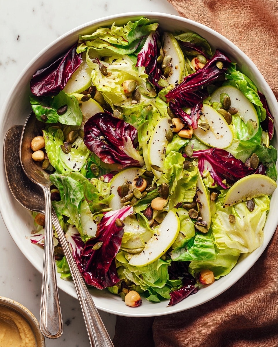Two white plates each hold a fresh salad with three layers: the bottom layer has mixed greens in light green and dark red shades, the middle layer shows thin pale yellow slices of pear arranged in a small stack, and the top layer has two dollops of creamy beige hummus sprinkled with black pepper, plus a few green pumpkin seeds and chickpeas scattered on top. On the right side of the nearest plate sits a silver fork. To the left of the plates is a small rustic bowl with more creamy hummus, and an orange cloth napkin lies nearby. The whole scene is set on a white marbled surface with soft natural light. photo taken with an iphone --ar 4:5 --v 7