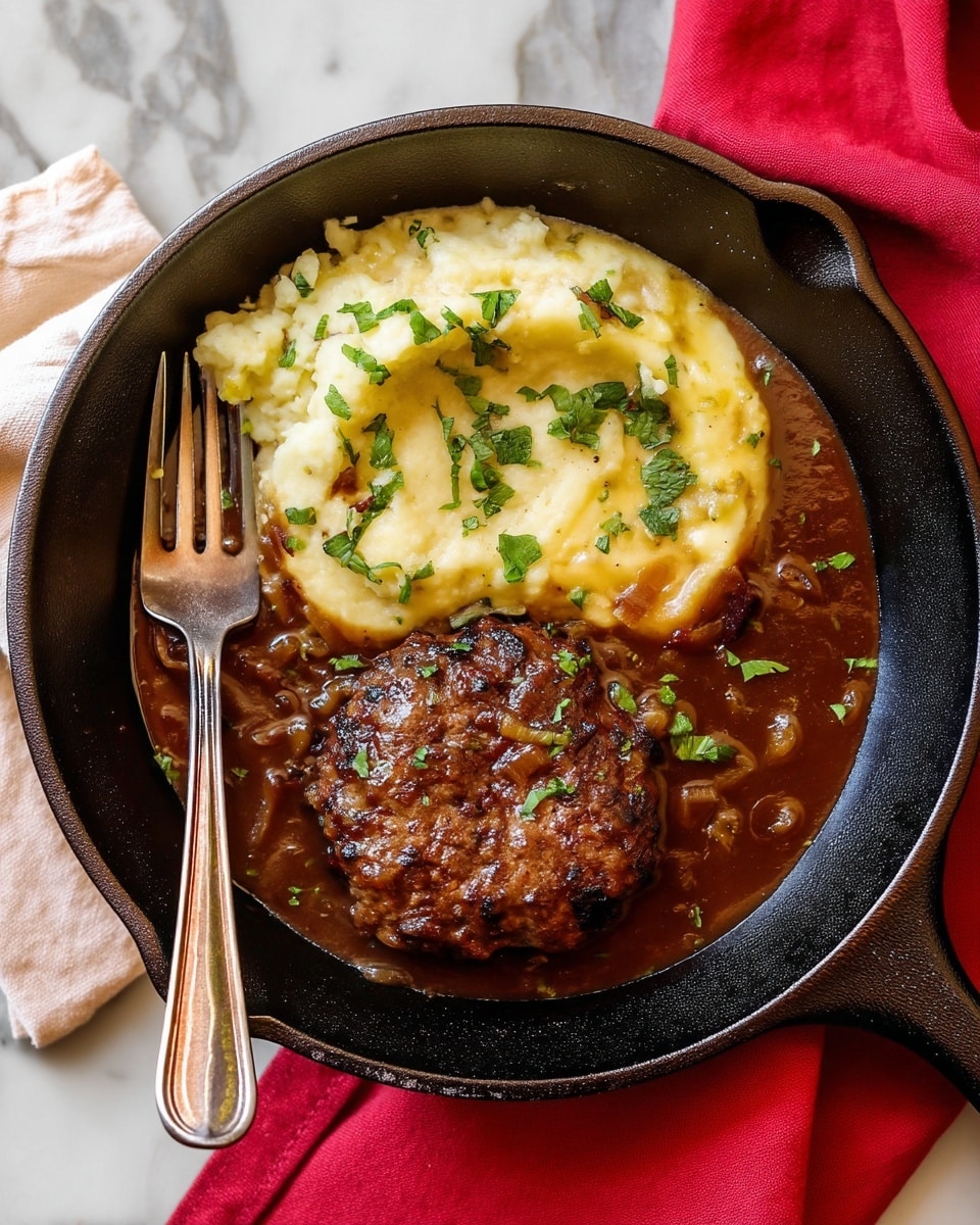 The image shows a black cast iron skillet holding two thick, round meat patties on the left side, with a rich brown color and a shiny glaze from cooked juices and caramelized bits. On the right side, there is a generous scoop of pale mashed potatoes with some browned spots from light frying or baking, garnished with small pieces of green herbs on top. A silver fork rests inside the skillet near the mashed potatoes. The skillet sits on a white marbled surface, with a bright red cloth partially visible in the background. photo taken with an iphone --ar 4:5 --v 7